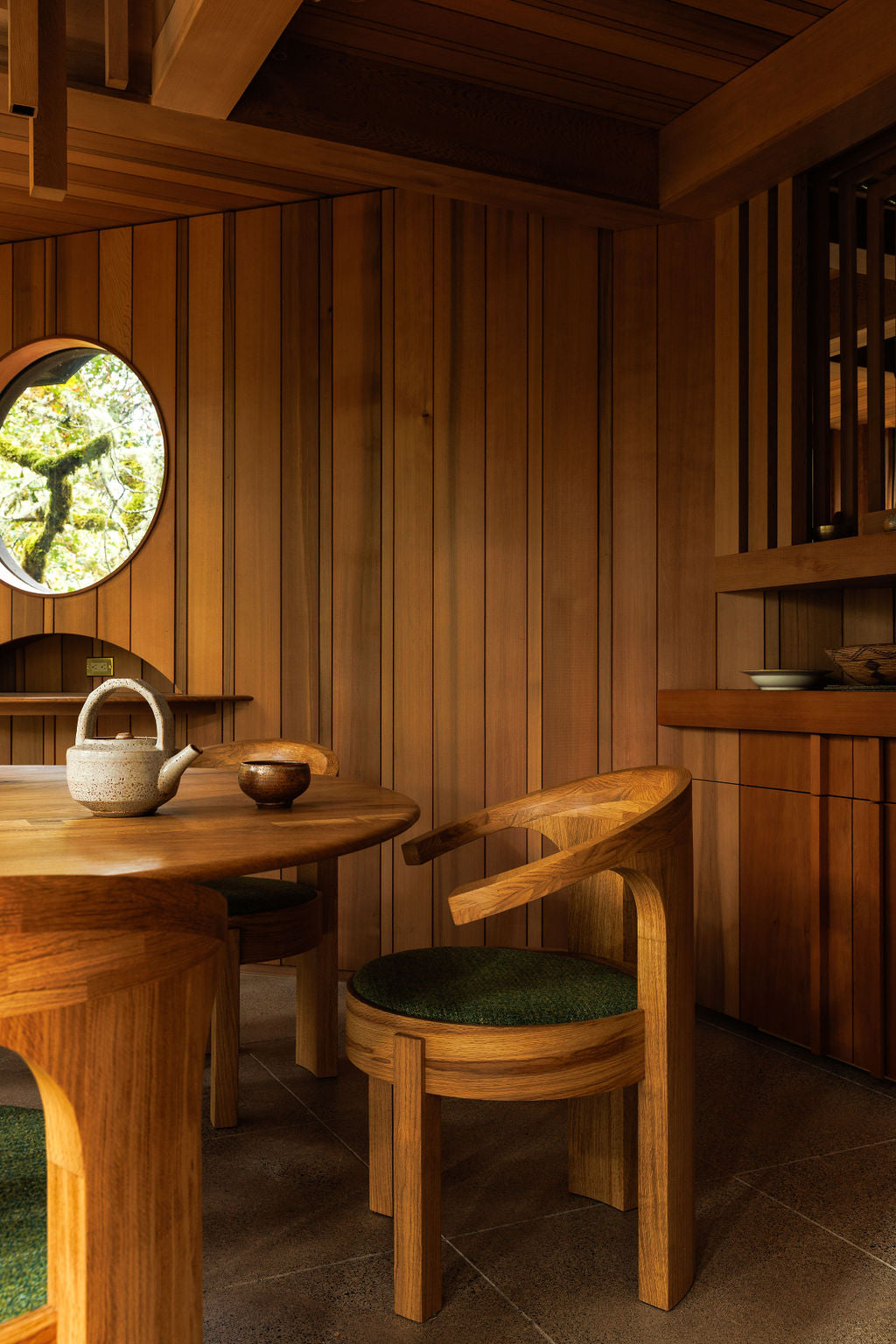 A handmade dining table and chairs in a wood-panelled room. All of the wood matches with a warm chestnut brown colour. 