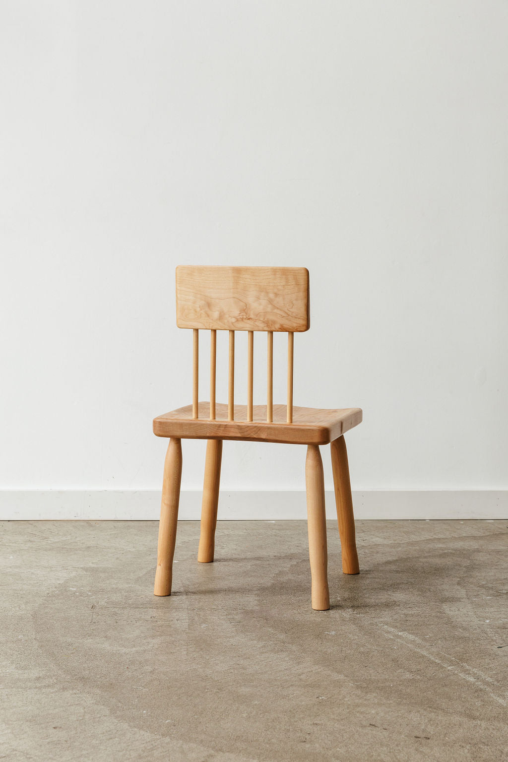 A light wood handmade modern minimal dining chair. Shot from the back.