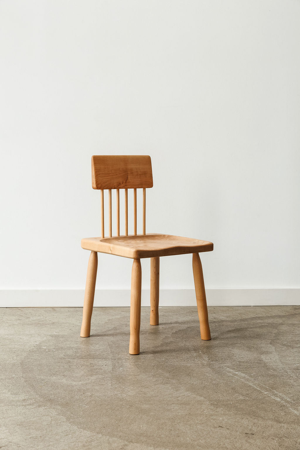 A light wood handmade modern minimal dining chair. Shot from the front. 