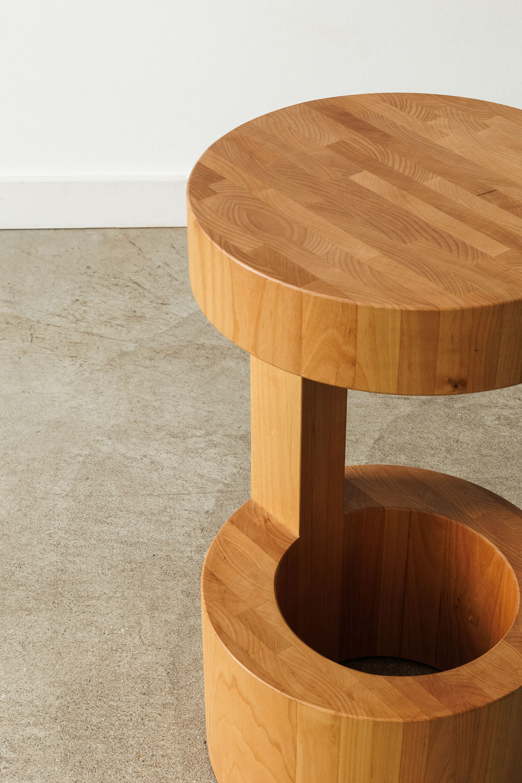 A circular custom wooden side table in a warm medium toned wood