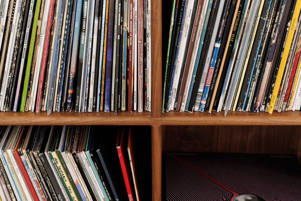 A close up view of a wooden shelf filled with vinyls