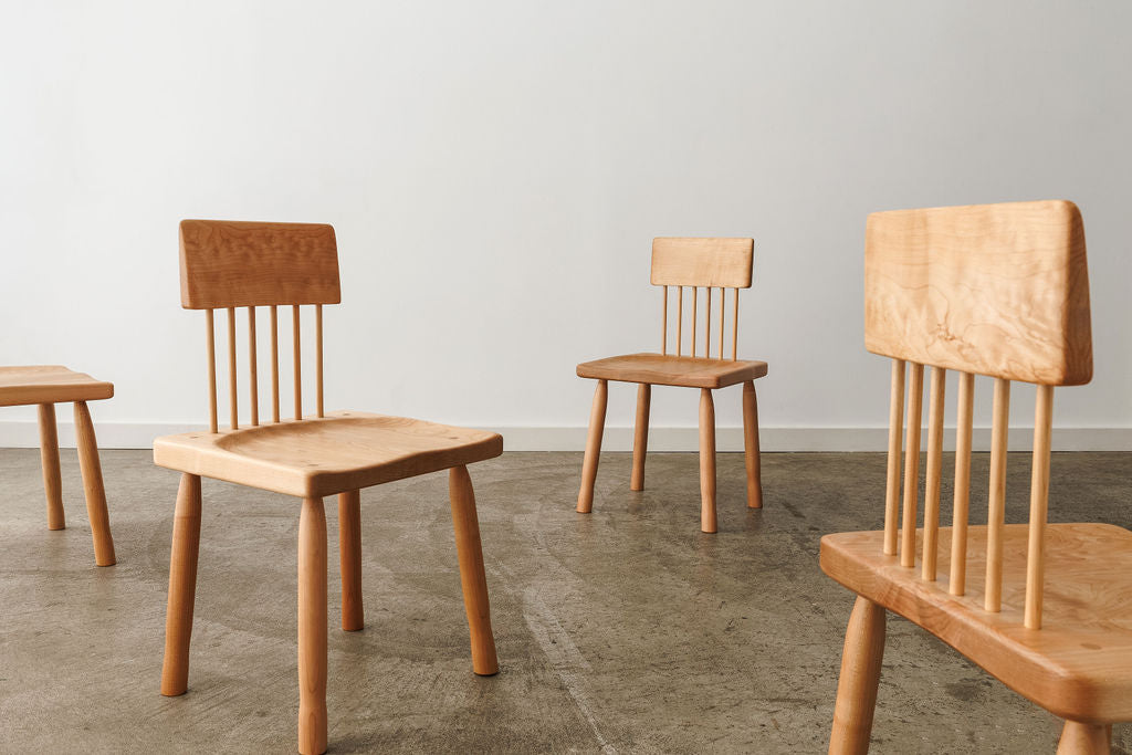 Four light coloured wooden chairs placed in an empty room, creating a minimalistic and inviting atmosphere.