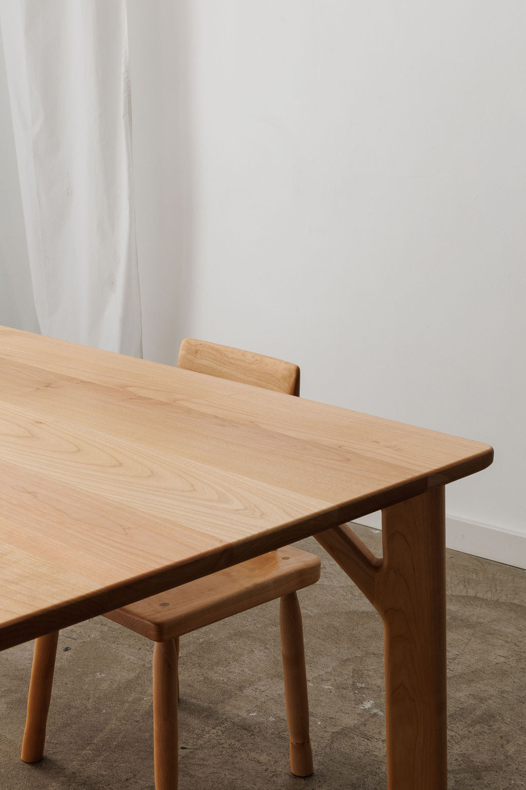 Light wood dining table with a matching wooden dining chair tucked in.